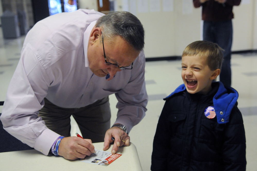 Gov. Paul LePage signs a leaflet Tuesday for a youngster at a polling place in Augusta. The governor ran a campaign that touched the electorate’s concerns about the economy.