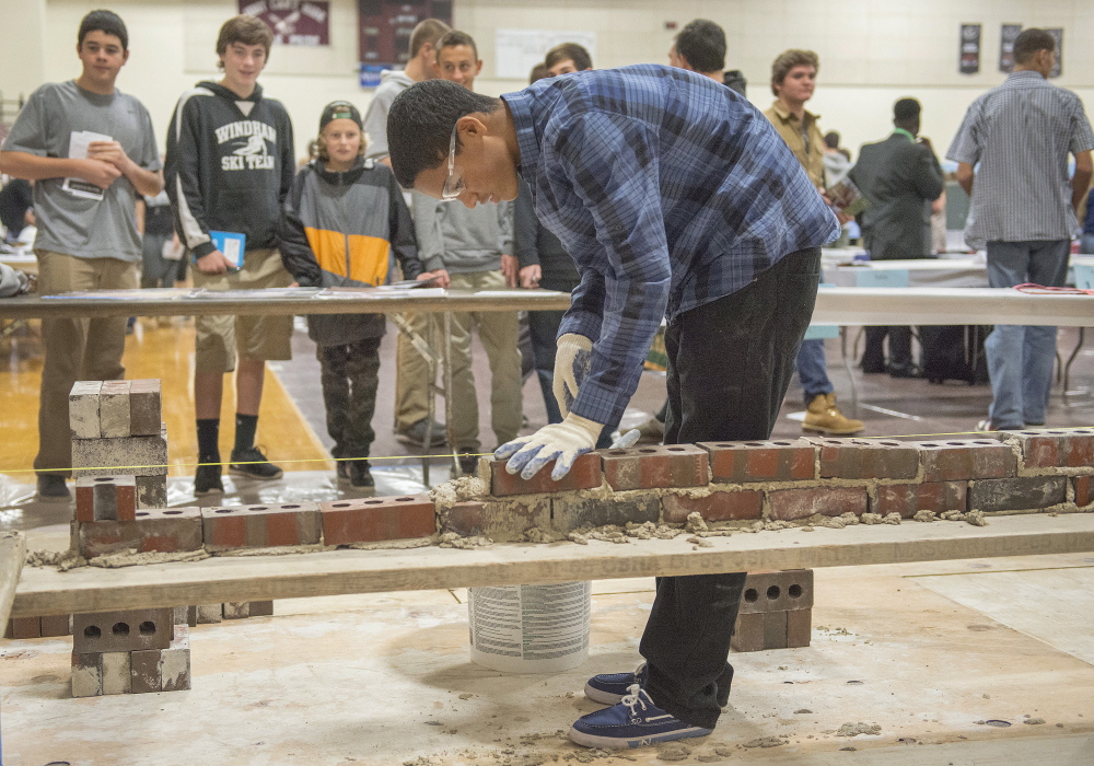 Windham High School sophomore Trevor Rogers adds bricks to a simulated wall during an interactive career fair Thursday at the school.