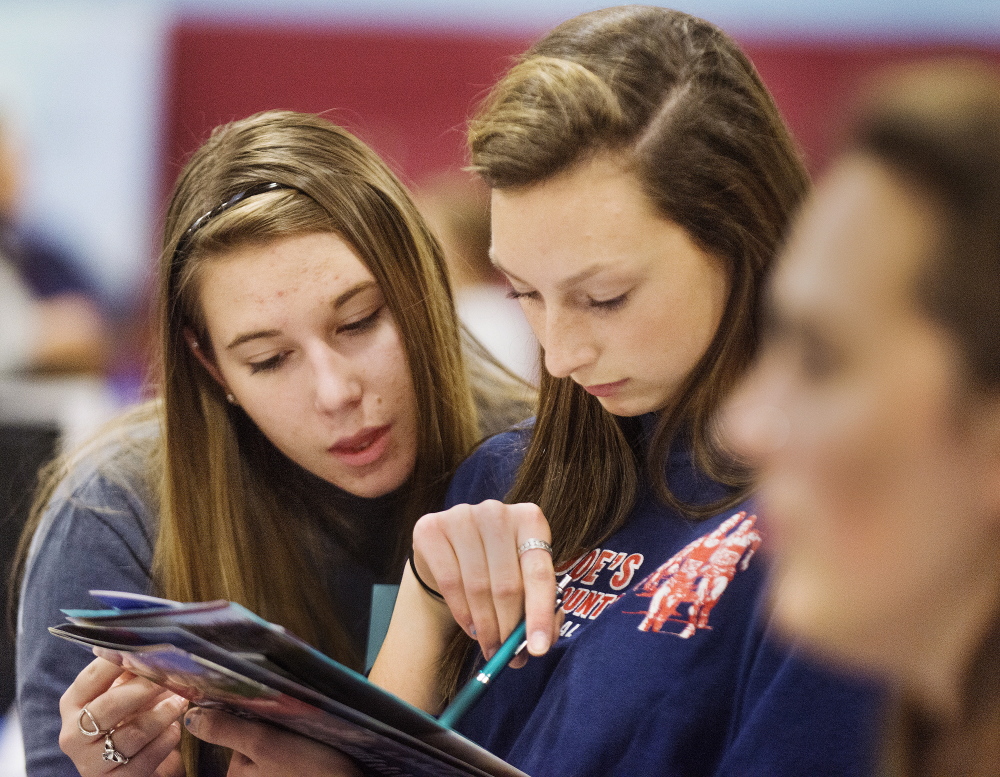 Melanie Aldrich, left, and Joelle Bochus, both juniors at Windham High, check out a  University of New Hampshire brochure at the fair.