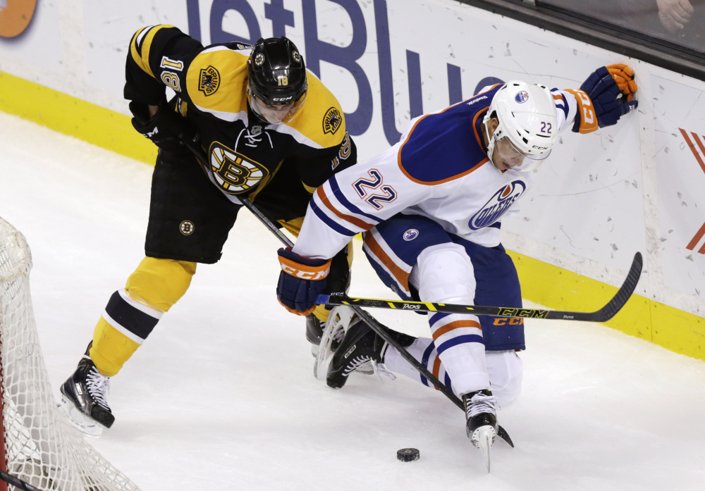 Boston Bruins right wing Reilly Smith and Edmonton Oilers defenseman Keith Aulie go for the puck during the third period of Thursday night’s game in Boston. The Bruins defeated the Oilers, 5-2.