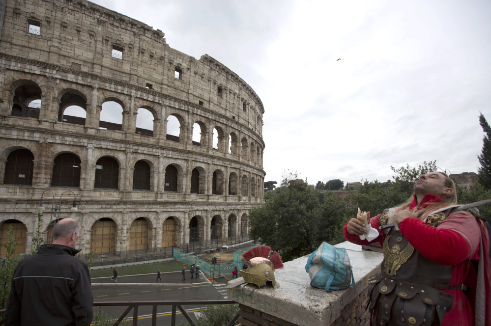 A man dressed as a gladiator enjoys his lunch in front of Rome’s Colosseum, on Friday. An archaeologist’s proposal to return the Colosseum’s storied arena to its original state has sparked a lively debate over appropriate uses of the monument that symbolizes the glories of ancient Rome. Critics have fretted that the Colosseum would be turned into a venue for events like rock concerts, viewed as both unbefitting its stature as an ancient wonder and likely to inflict damage to the structure already weakened by earthquakes, notably in 443 and most recently in the 1700s.