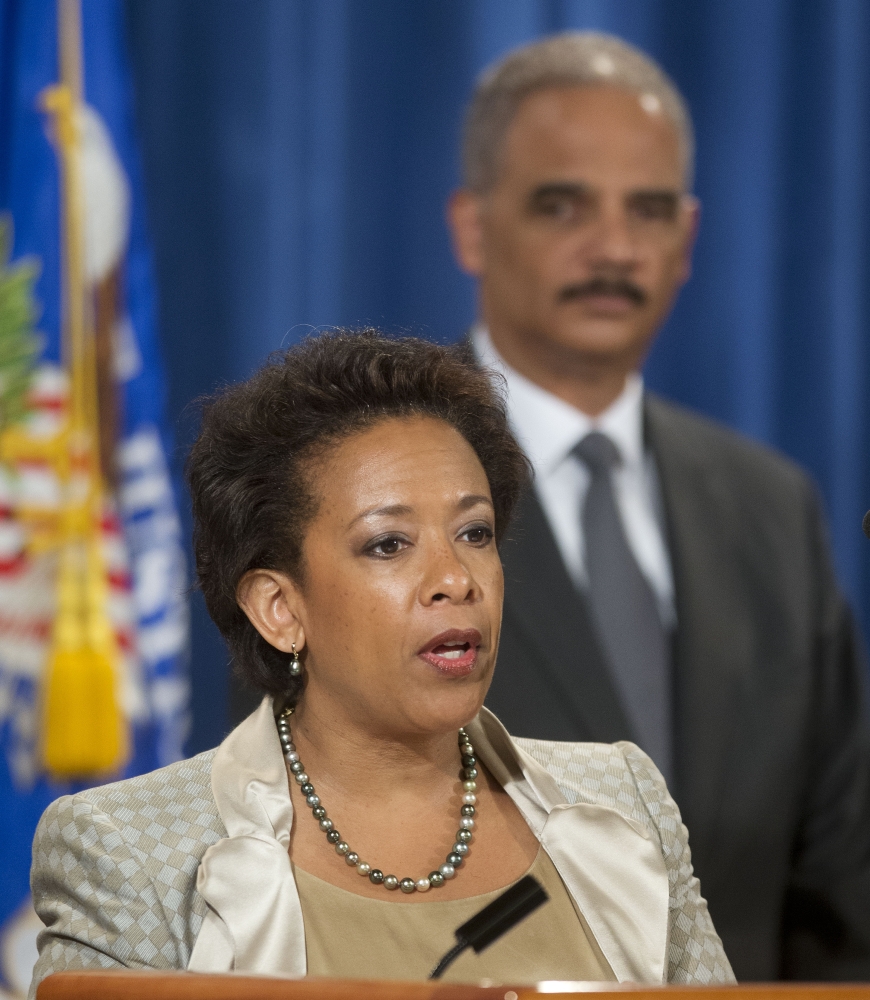 Attorney General Eric Holder listens to Loretta Lynch during a July 28 news conference in Washington.