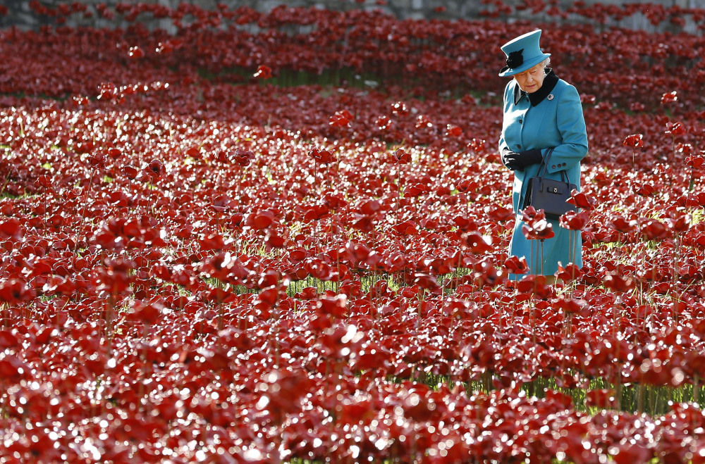 Britain’s Queen Elizabeth II walks through a field of ceramic poppies at The Tower of London. This year, the centenary of WWI, the poppy is more ubiquitous than ever.