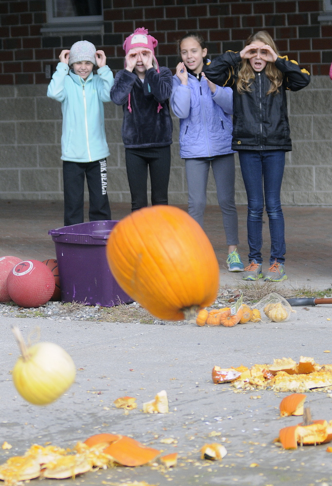 Maranacook Community Middle School students watch pumpkins hit the pavement Monday at the school in Readfield after being dropped from a Central Maine Power bucket truck. The students were learning about Newton’s laws of physics for a class.