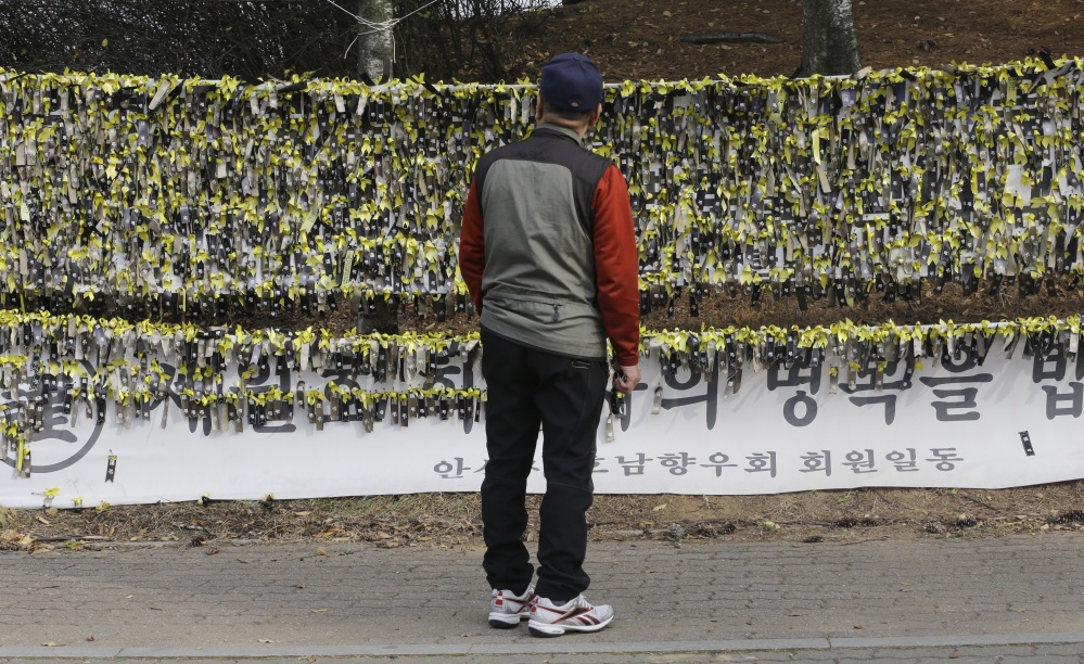 A man looks at messages written on ribbons for missing passengers and victims aboard sunken ferry Sewol near a group memorial altar in Ansan, South Korea.
