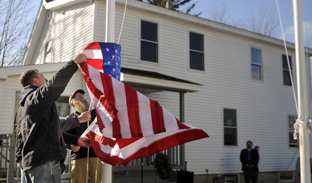 Veterans raise the colors Tuesday on the new flagpoles that were dedicated at the Bread of Life Ministries Veterans Shelter in Augusta. Shelter residents helped erect the poles and raised the flags.