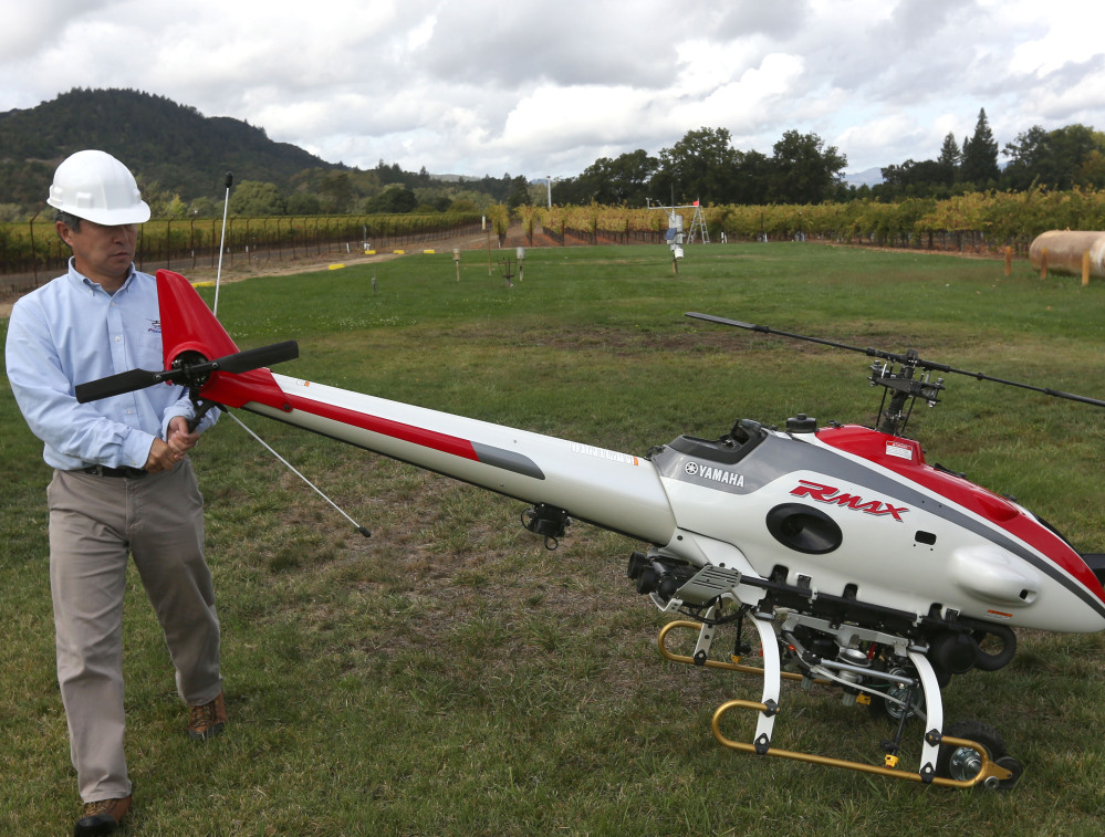 A worker puts an RMax unmanned helicopter into position for a demonstration flight. The FAA’s near-total ban on drone use has been largely ignored.