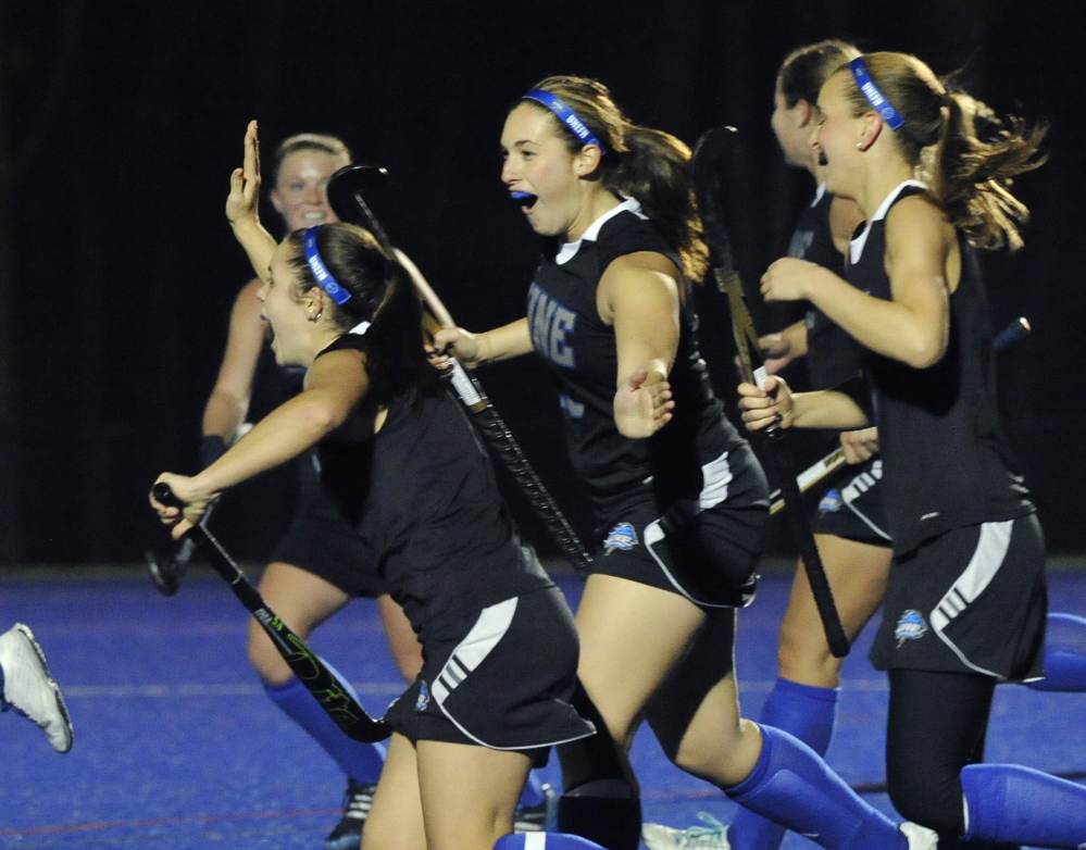 Erin Bibber, left, is congratulated by Olivia Madore and the rest of the team after scoring on a rebound – the first goal of the NCAA tournament game against Simmons.