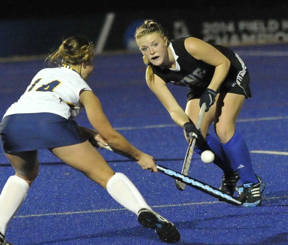 Alyssa Kowal of the University of New England hits the ball past Marra Wagner of Simmons during UNE’s 2-0 victory Wednesday night in NCAA field hockey.