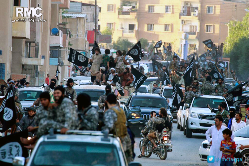 Fighters from the Islamic State group parade in Raqqa, north Syria, in June. In the early dawn of Nov. 2, militant leaders with the Islamic State group and al-Qaida agreed to stop fighting each other and work together against their opponents, a prominent Syrian opposition official and a rebel commander said.