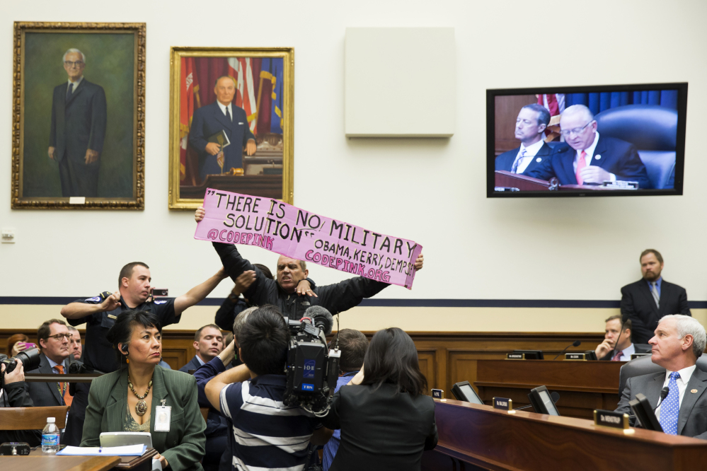 A CodePink protester is removed by police on Capitol Hill in Washington after interrupting a House Armed Services Committee hearing Thursday with Defense Secretary Chuck Hagel, and Joint Chiefs Chairman Gen. Martin Dempsey on the Islamic State .