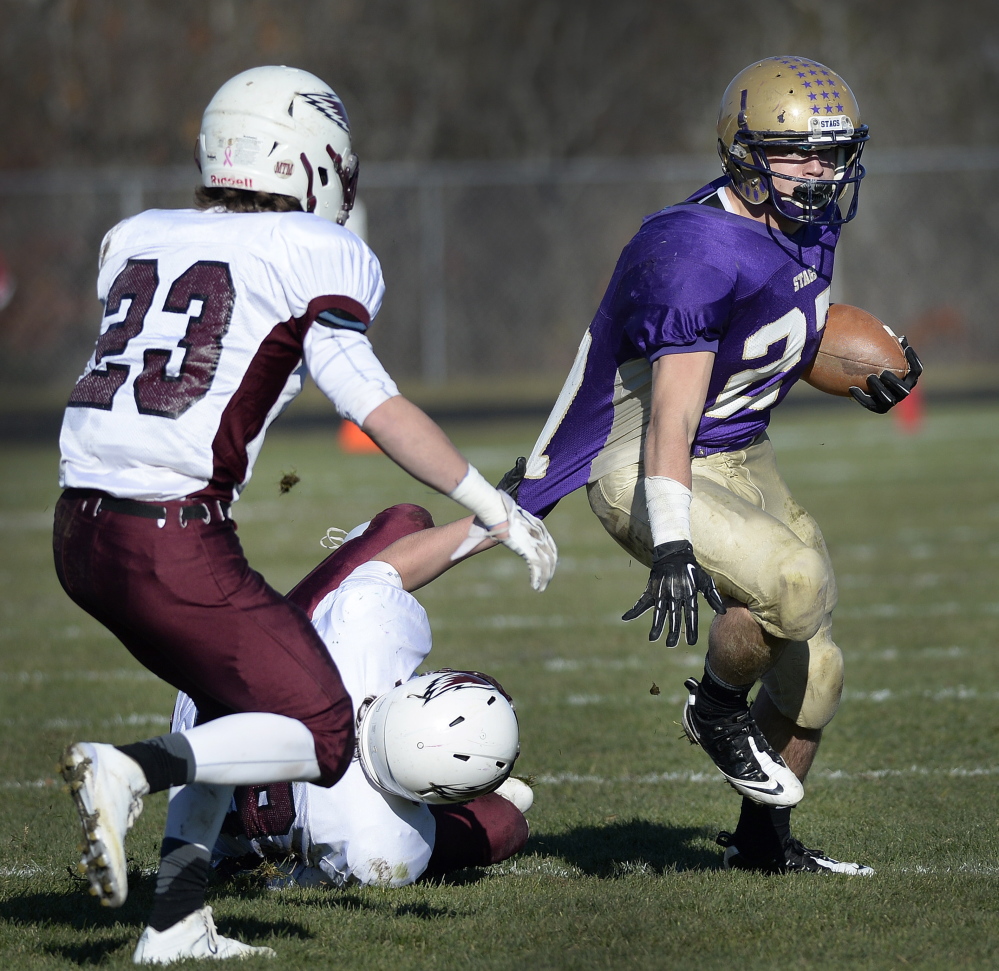 Joe Fitzpatrick, who gained 177 yards for Cheverus while dealing with a pulled muscle, attempts to break away from Griffin Jacobson of Windham as Tanner Laberge moves in during Windham’s overtime victory Saturday.