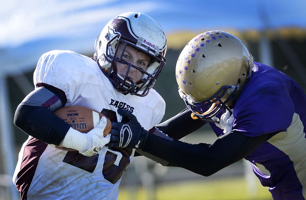 Dylan Koza of Windham attempts to break away from a Cheverus defender and gain extra yardage Saturday during their Eastern Class A championship game at Cheverus High. Windham rallied from a 14-3 deficit in the fourth quarter for a 21-20 overtime victory.