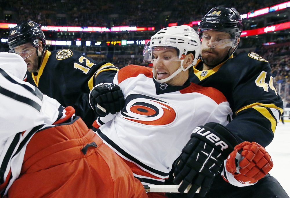Carolina Hurricanes’ Zach Boychuk, second from right, and Boston Bruins’ Dennis Seidenberg battle for the puck during the first period Saturday at Boston.