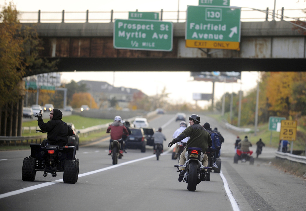 ATV and dirt bike riders cruise illegally on a city street in Bridgeport, Conn. Groups of such riders gather through word of mouth or social media to ride through cities, pulling stunts and evading police.