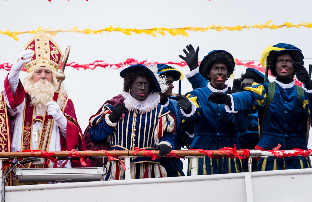 Actors dressed as Saint Nicholas, left, and Black Pete arrive on a boat in Antwerp, Belgium, on Saturday. Some say Black Pete is a racist caricature.