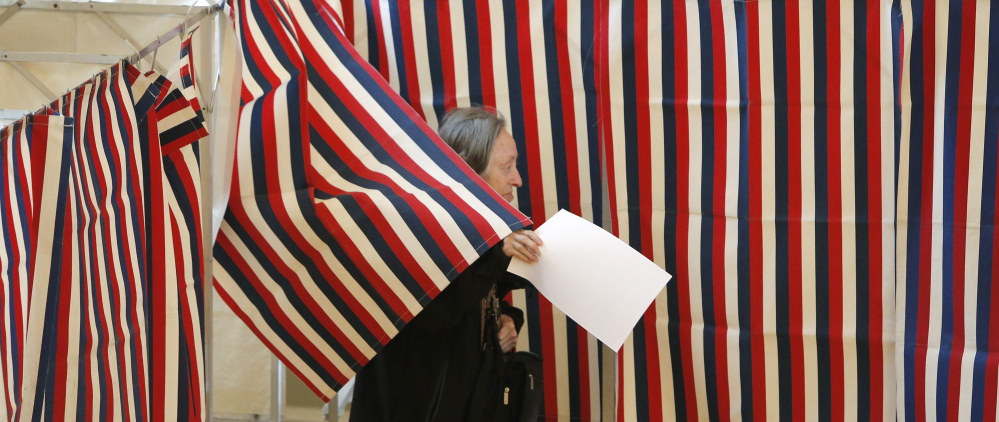 Ballots in hand, a woman leaves a voting booth at Kennebunk Town Hall on Nov. 4. A group behind subtly threatening mailers that went out to some Maine voters used personal data from Maine’s Central Voter Registration database, which contains detailed information about members of the state’s electorate, including party affiliation and when they voted. Gregory Rec/Staff Photographer