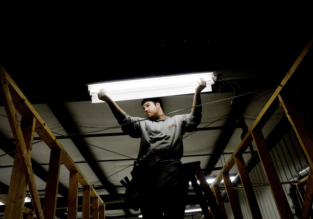 Ryan Lambert of Superior Electrical Contracting installs new lighting at Cuddledown in Yarmouth, in a project aided by a $14,741 grant from Efficiency Maine. The Public Utilities Commission voted in March to restrict funding for energy efficiency programs.