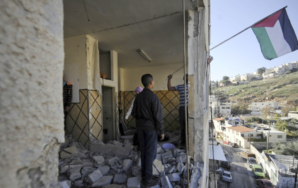 Palestinians hang a flag in an apartment in Jerusalem on Wednesday. Israeli officials demolished the home in response to a deadly attack on a Jerusalem train station last month.