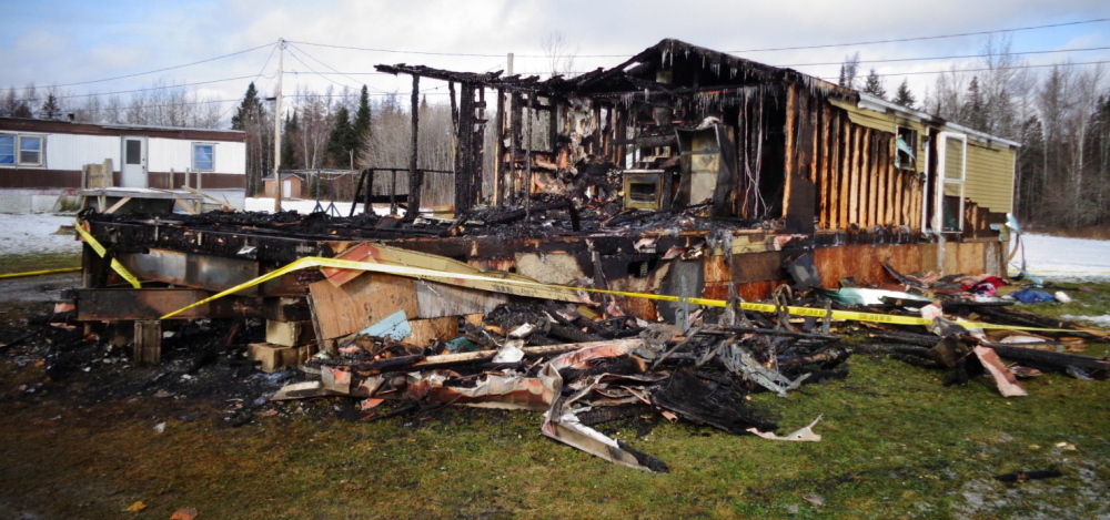 The remains of a mobile home in which four people died Thursday are cordoned off by police tape in Caribou, in this photo provided by Maine State Police.