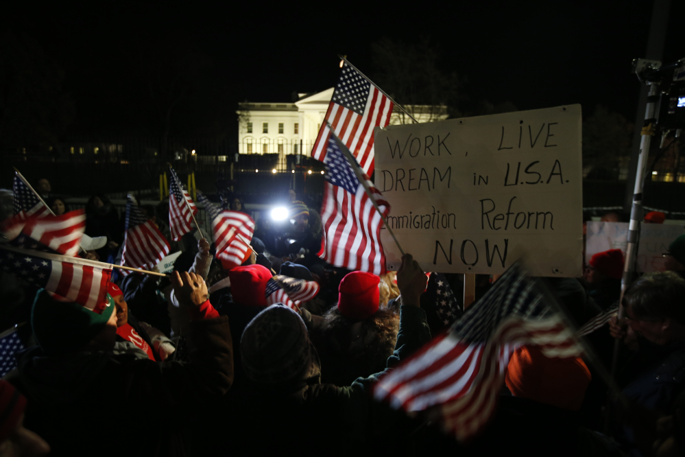Rally participants wave American flags and signs in front of the White House on Thursday before President Obama’s announcement of far-reaching orders on immigration that will allow nearly 5 million people now in the U.S. illegally to “come out of the shadows and get right with the law.”