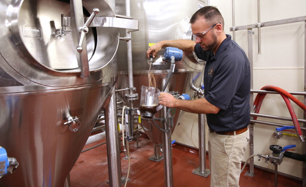 John Kimes, a MillerCoors pilot brewer, pours a sample of the Fred Miller chocolate lager in the fermenting and aging cellar.