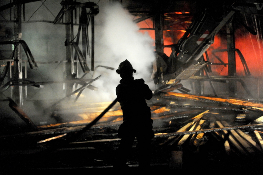 A firefighter hoses down burning lumber at Campbell’s True Value Building Suppy in Madison on Thursday night.