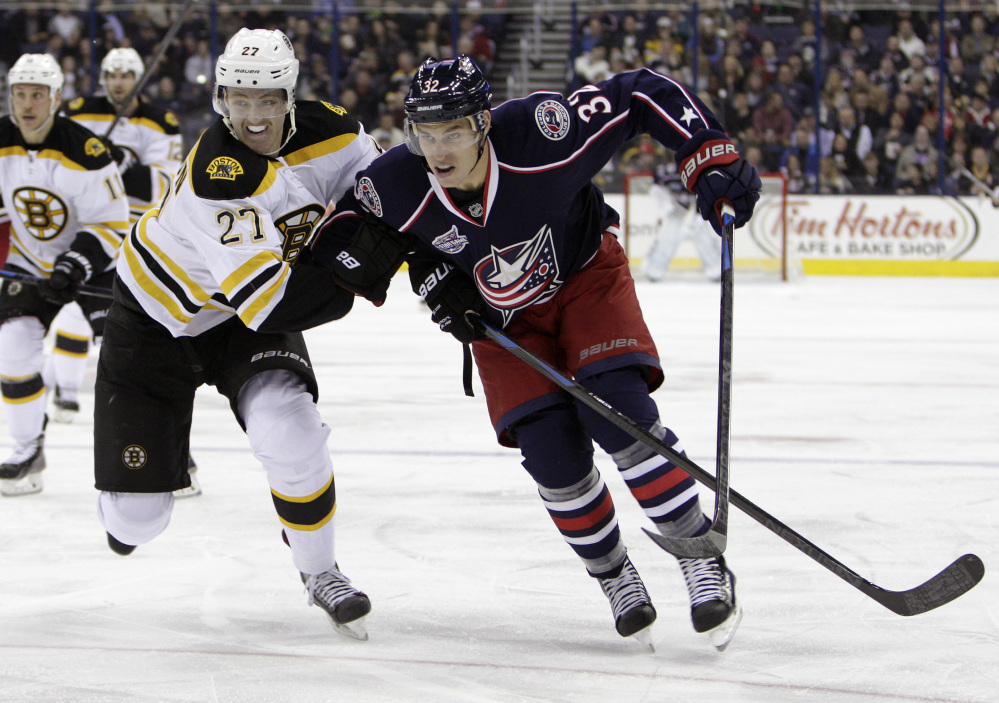 Boston Bruin Dougie Hamilton, front left, and Columbus’ Adam Cracknell chase a loose puck during the second period of Friday night’s game. The Bruins won in overtime, 4-3.