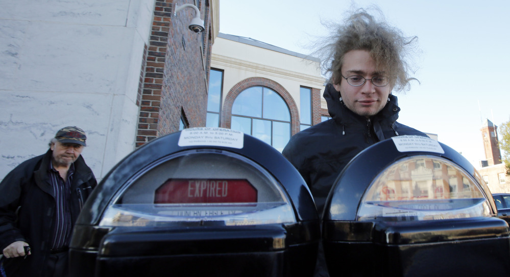 Garret Ean, a self-proclaimed “Robin Hooder,” puts money in expired meters before a parking enforcement officer in Keene, N.H., can write a ticket. The activists In Keene say they are protesting “the King’s tarrif” – or what they see as government oppression.