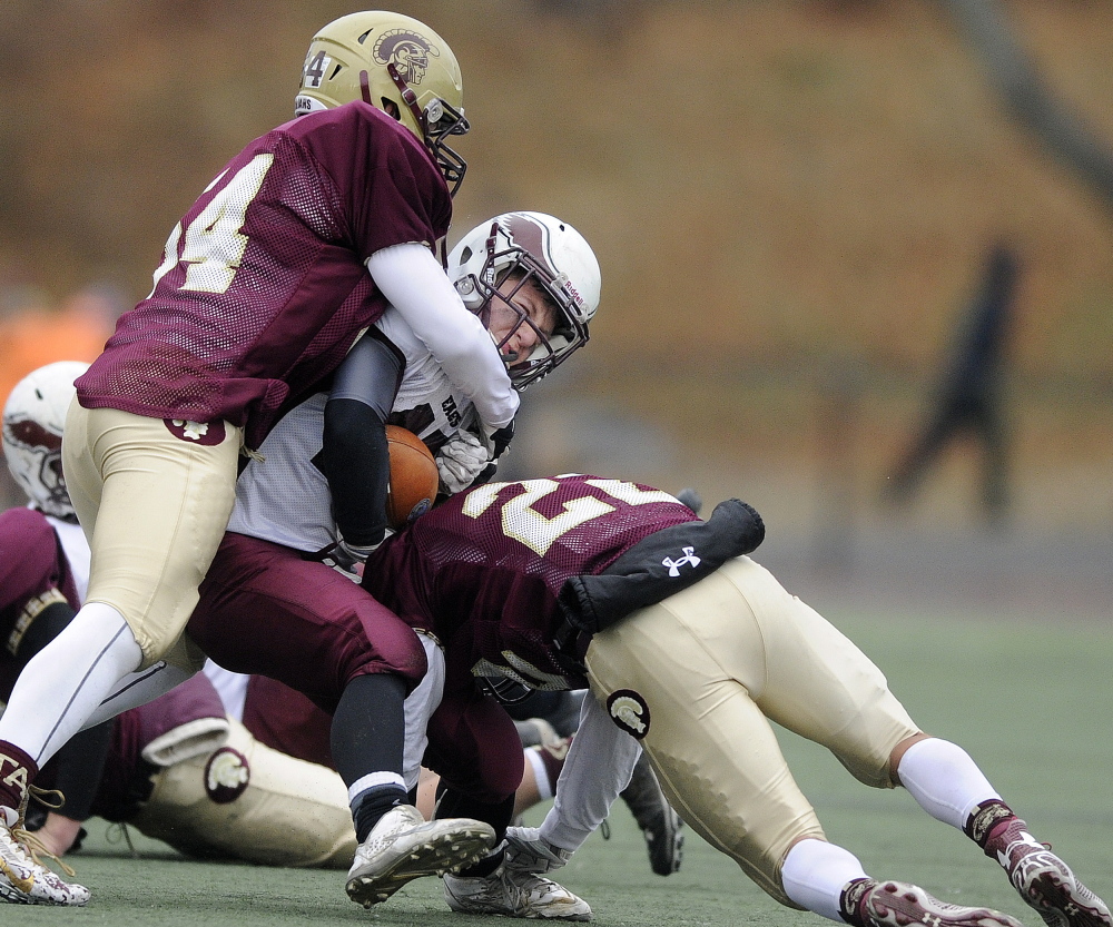 Windham running back Dylan Koza is hauled down by Thornton Academy defenders Dederick Eastup, left, and Nathan Watson during the second half of the Class A final. The Golden Trojans shut out Windham in the second half as they rallied for a 35-14 win, earning their second state championship in three seasons.
