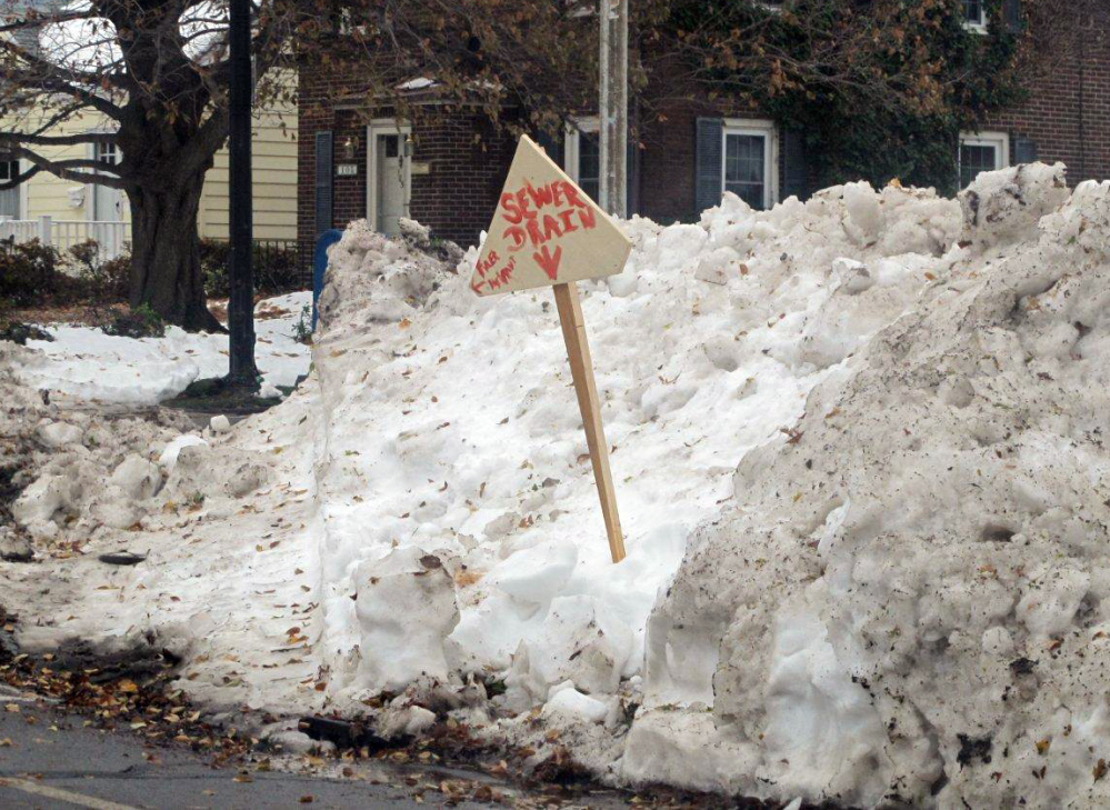 A sign marks the location of a snow-covered sewer drain and fire hydrant along McKinley Parkway in Buffalo, N.Y., Monday. With temperatures approaching 60 degrees following more than 7 feet of snow in spots last week, the region was bracing for possible flooding.