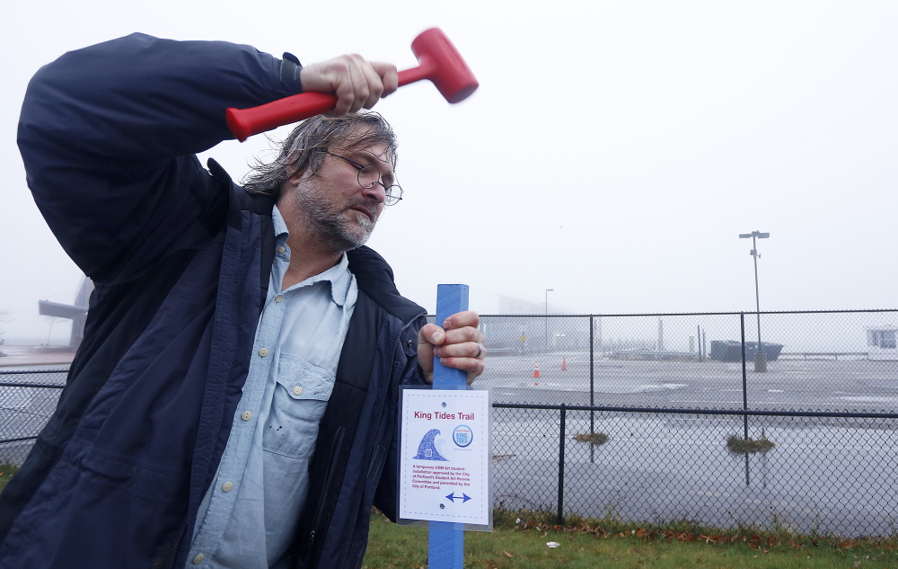 Ken Gross, a graduate student at the University of Southern Maine, posts a sign marking where the water line would be along part of the Portland waterfront if a 3-foot rise in sea level occurs by the year 2100, as some research has suggested.
