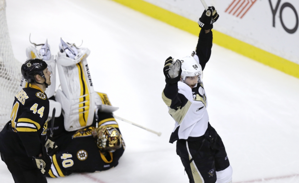 Pittsburgh Penguins defenseman Kris Letang celebrates the game-winning goal by teammate Evgeni Malkin as Boston Bruins goalie Tuukka Rask rolls over at the end of Monday night’s game. The Penguins defeated the Bruins, 3-2.