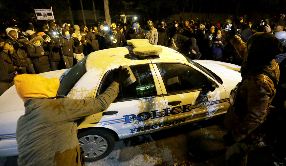 Protesters vandalize a police car outside Ferguson’s city hall Tuesday night. It was the second night of unrest in Ferguson, after a grand jury’s decision not to indict police officer Darren Wilson in the fatal shooting of Michael Brown.