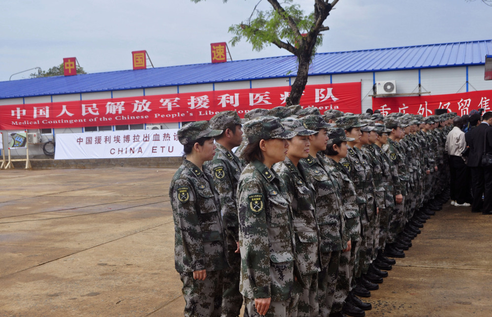 Chinese soldiers stand outside the new Ebola virus treatment center sponsored by China in Monrovia, Liberia, on Tuesday. The 100-bed clinic will begin taking patients next week.