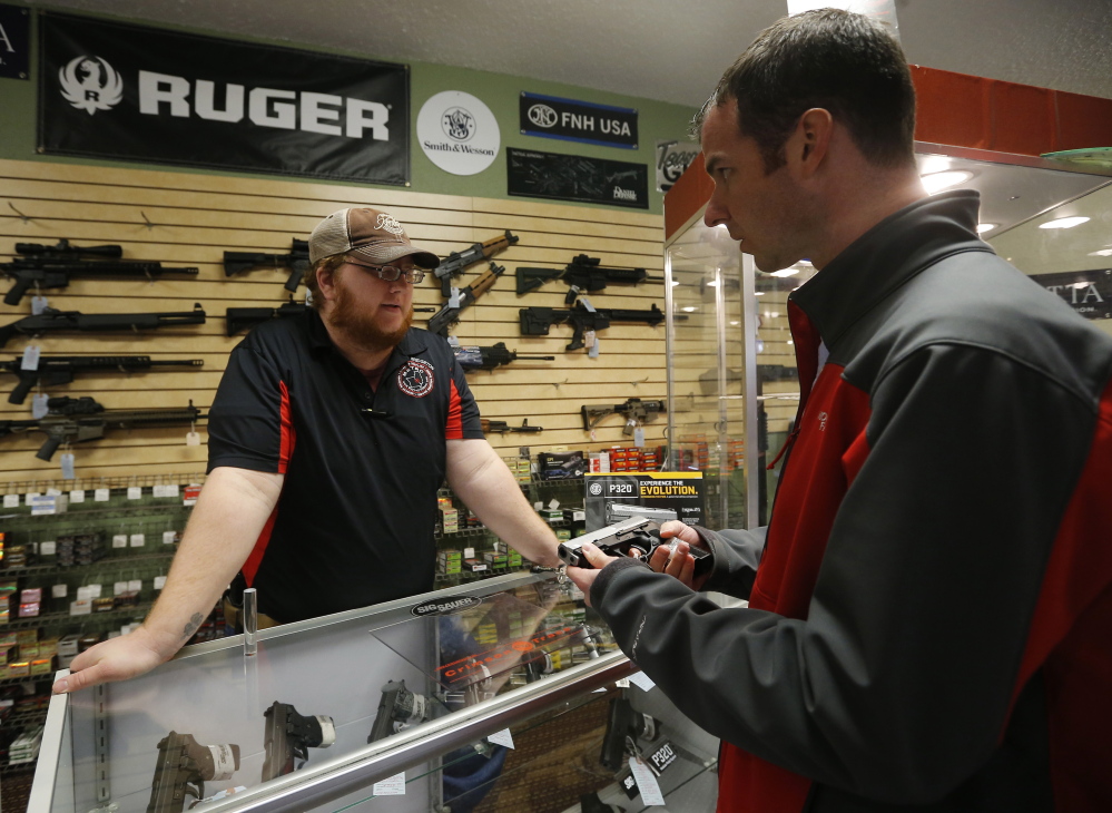 Metro Shooting Supplies employee Chris Cox, left, speaks to customer Steve Christy about the purchase of a 9mm handgun at the shop in Bridgeton, Mo.