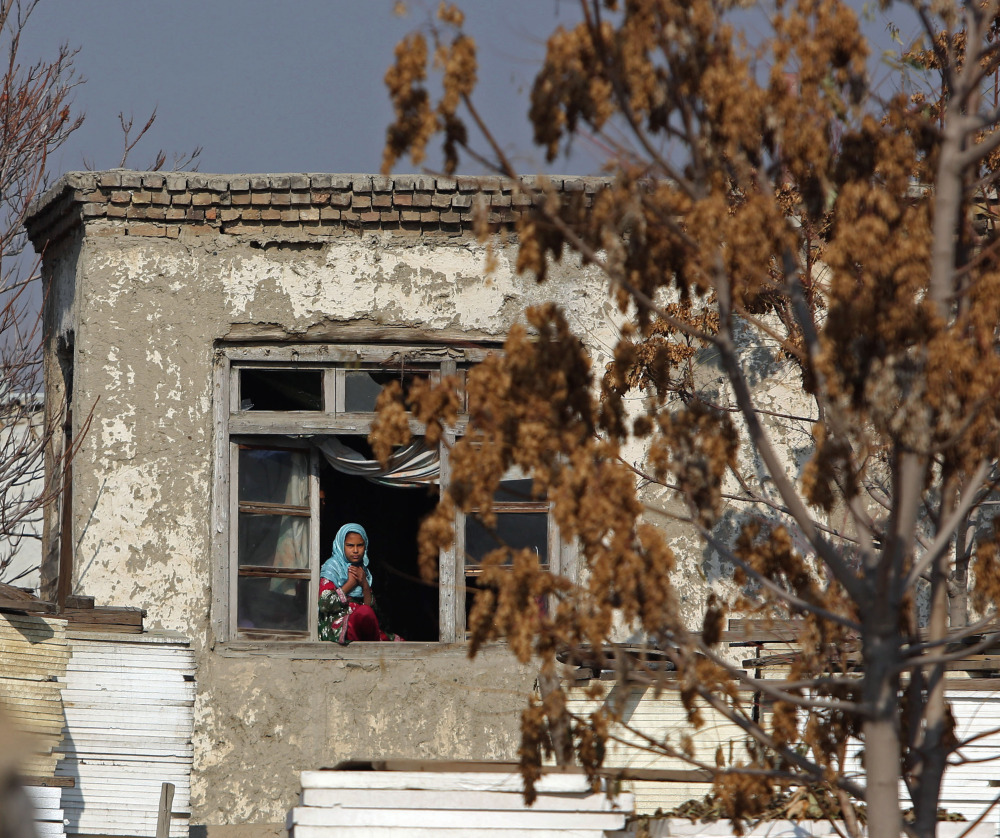 An Afghan girl looks out from her home near the site of a Taliban attack Thursday in Kabul. Attacks on international personnel and Afghan civilians have jumped in the past week.