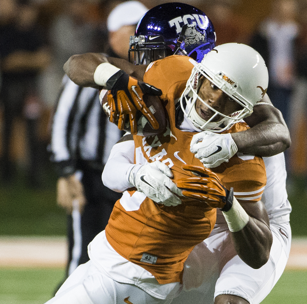 John Harris of Texas keeps a grip on the ball as he is hit by George Baltimore of Texas Christian during TCU’s 48-10 win Thursday night. TCU remains in the hunt for a Big 12 title.