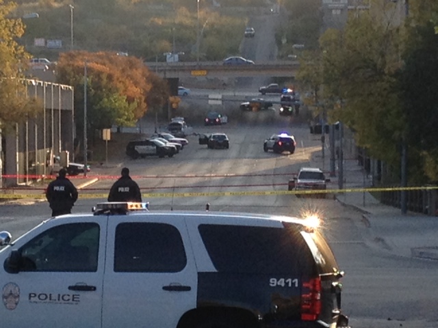 Police tape marks off the scene after a man opened fire on the Mexican Consulate, police headquarters and other downtown buildings early Friday in Austin, Texas. In the distance, police cars surround the suspect’s vehicle parked near the Interstate 35 overpass.