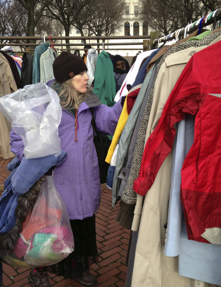 Mary Frawley of Cranston, R.I., looks for a coat on the Statehouse lawn Friday in Providence, R.I. Winter coats were given away as part of the annual “Buy Nothing Day.”