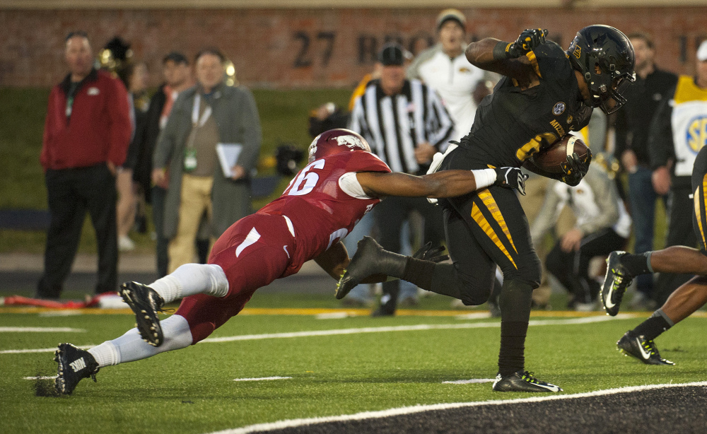 Missouri running back Marcus Murphy, right, drags Arkansas’s Rohan Gaines into the end zone as he scores the winning touchdown during the fourth quarter of Friday’s game in Columbia, Mo.