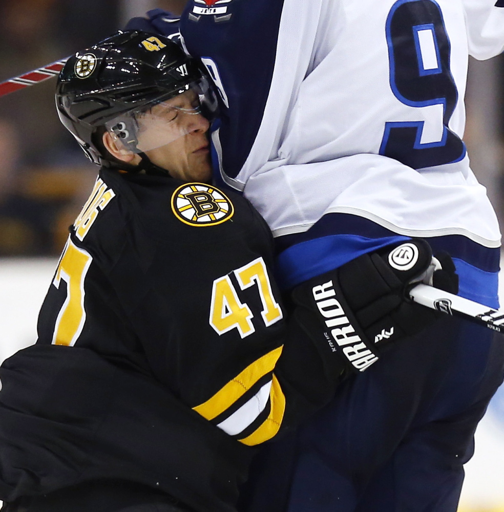 Boston’s Torey Krug might bow to no one but still takes a solid hit from Winnipeg’s Evander Kane during the second period of Friday night’s game in Boston, won by the Bruins in overtime.