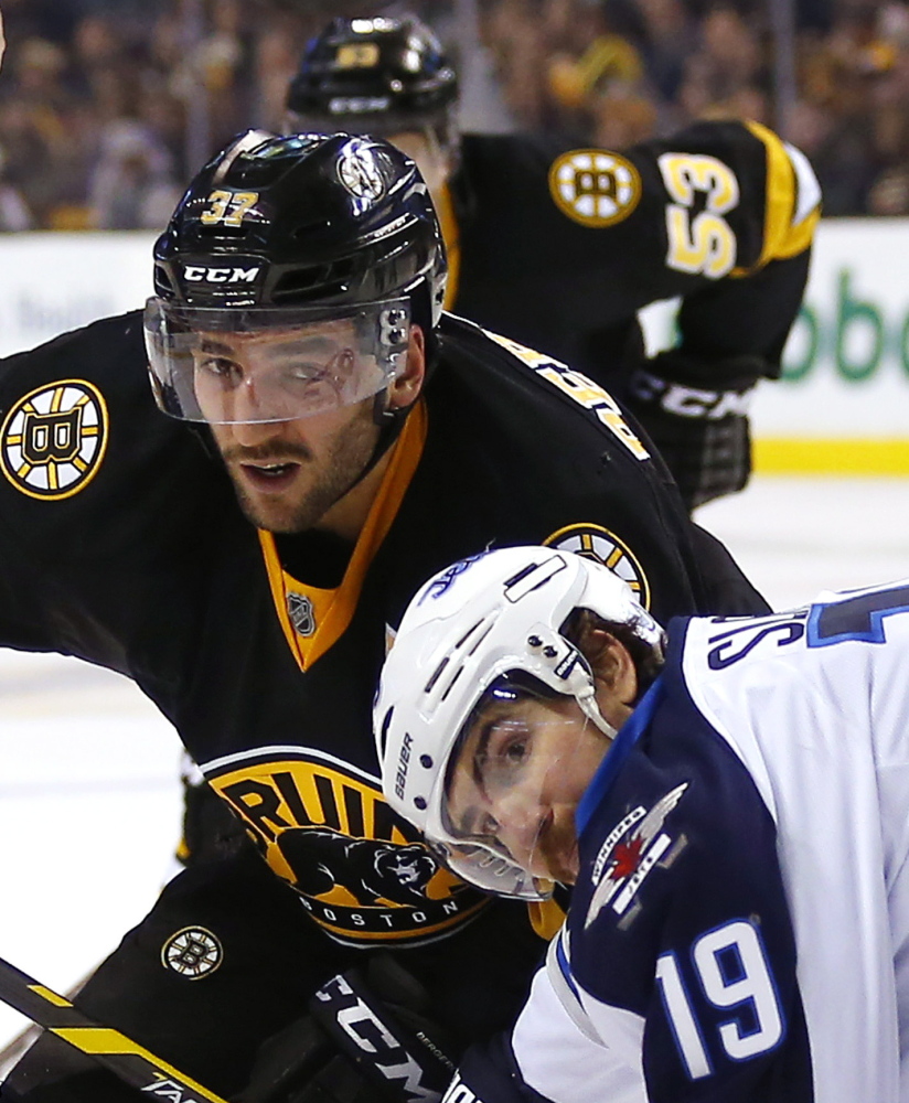 Boston’s Patrice Bergeron and Winnipeg’s Jim Slater are all eyes as they battle for a loose puck during the second period of the Bruins’ come-from-behind victory at home.