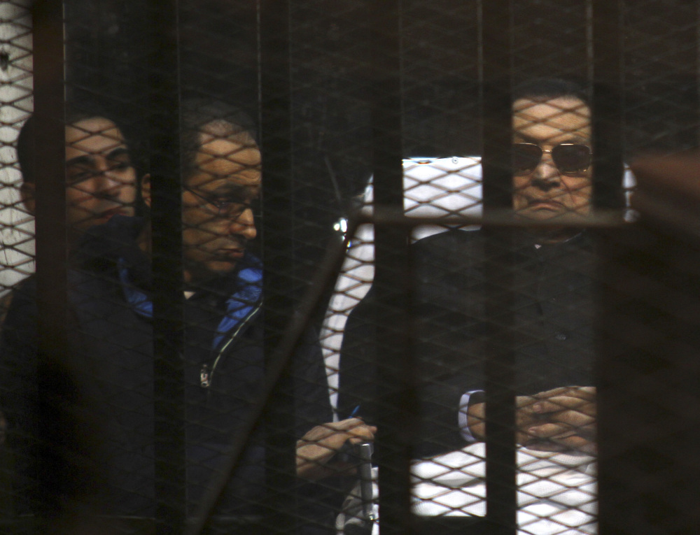 Ousted Egyptian President Hosni Mubarak, 86, lies on a gurney, next to his son, Gamal, second left, in the defendant’s cage, during a court hearing in Cairo, Egypt, Saturday. An Egyptian court on Saturday dismissed murder charges against Mubarak in connection with the killing of protesters in the 2011 uprising that ended his nearly three-decade reign.