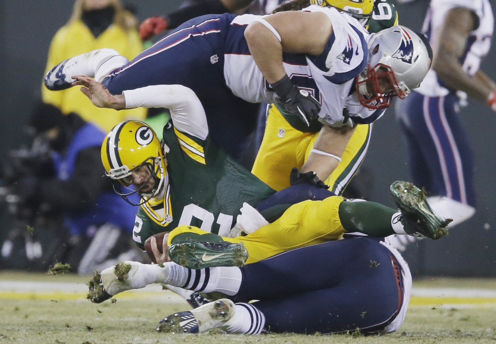 Green Bay Packers quarterback Aaron Rodgers is sacked by New England Patriots’ Dont’a Hightower and Zach Moore (90) during the first half Sunday in Green Bay, Wis.