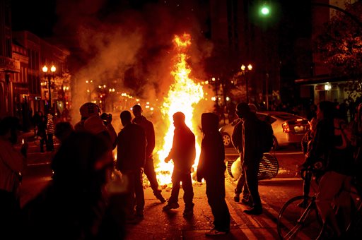 Protesters gather around burning refuse in Oakland, Calif., on Tuesday after the announcement that a grand jury decided not to indict Ferguson police officer Darren Wilson in the fatal shooting of Michael Brown, an unarmed 18-year-old. Several thousand protesters marched through Oakland with some shutting down freeways, looting, burning garbage and smashing windows. The Associated Press