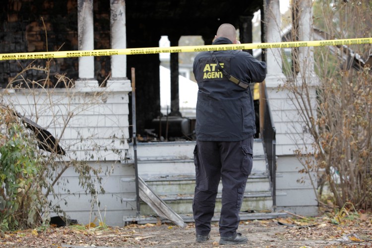 An agent with the Bureau of Alcohol, Tobacco, Firearms and Explosives photographs the house at 20 Noyes St. in Portland Monday. Investigators are still trying to determine the cause.