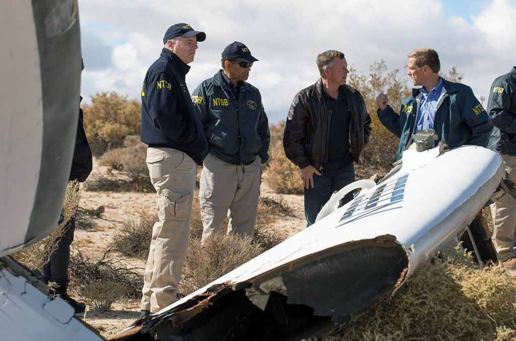 Virgin Galactic pilot Todd Ericson, right, talks with National Transportation Safety Board Acting Chairman Christopher A. Hart, second from left, at the SpaceShipTwo accident site with investigators in Mojave, Calif., on Saturday. Investigators have found that the "feathering" system, which rotates the tail to create drag, was activated before the craft reached the appropriate speed. NTSB photo