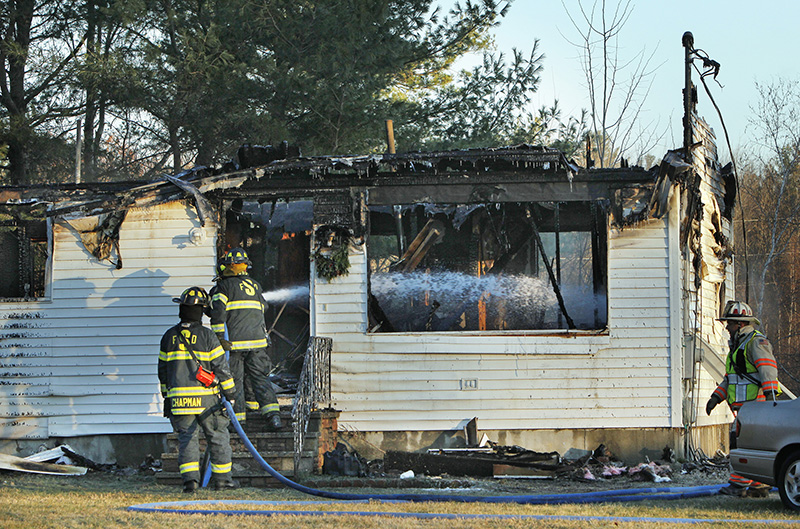 Saco firefighters douse hot spots in a building on Alfred Road in Biddeford that caught fire on Friday morning.
