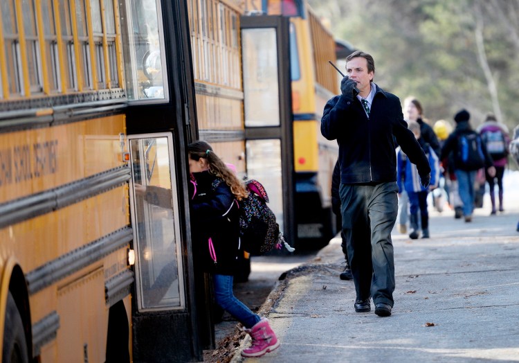 Windham Primary School Principal Kyle Rhoads talks on a radio as students board buses to leave school Monday morning after a threatening email message prompted Regional School Unit 14 to release students from all of its schools in Windham and Raymond. The schools will be closed again Tuesday.